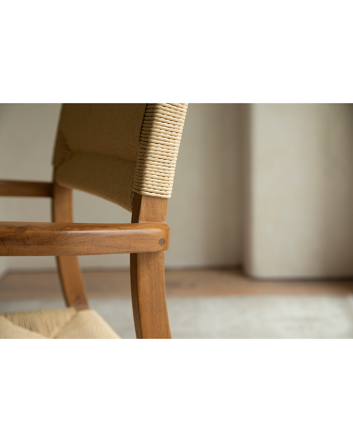 Close-up of Reed Chair showcasing woven backrest and teak armrest detail.