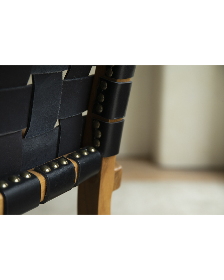 Close-up of Reed Chair's black woven leather seat with brass detailing.