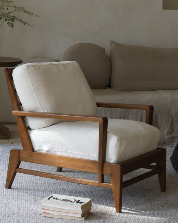 Modern vintage lounge chair with wooden frame and beige cushions in a living room