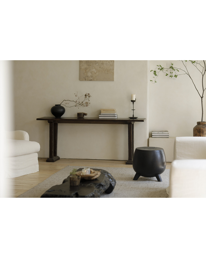 Minimalist living room with black wooden side table and elegant decor.