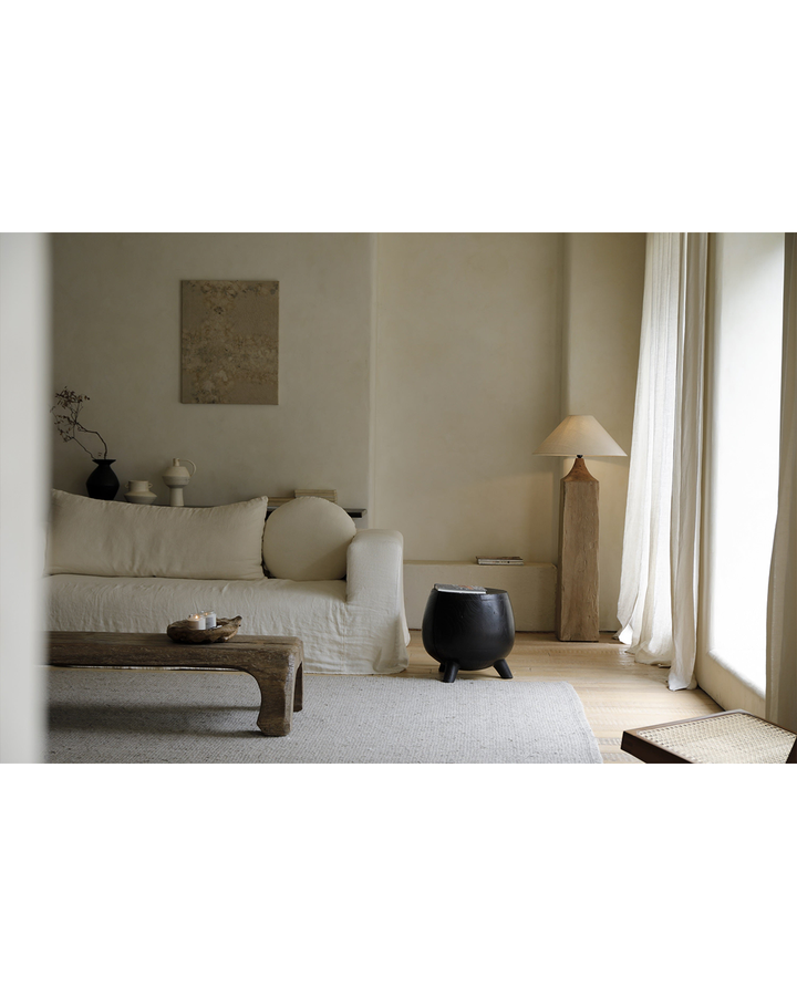 Black wooden side table beside beige sofa in a cozy minimalist living room.