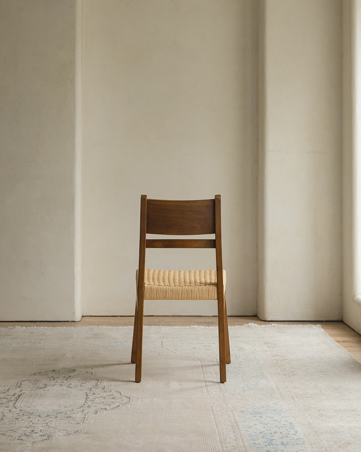 Beam Chair with woven seat viewed from back in a minimalist room