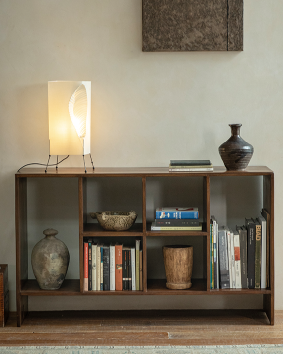 Wooden bookcase with books, vintage vases, and a lamp in a modern vintage setting