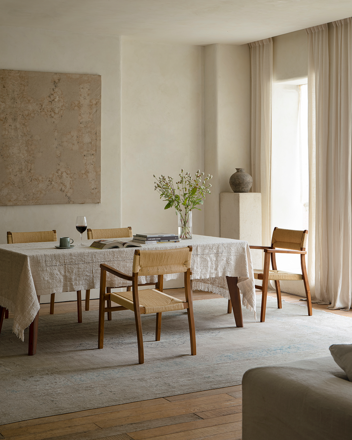 Modern dining room with Reed Chairs around a wooden table and natural floral arrangement.