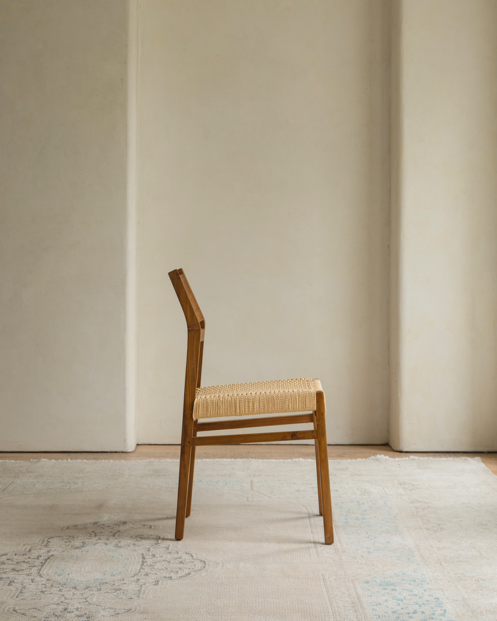 Side view of Beam Chair with woven seat in minimalist interior setting.