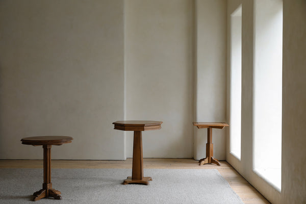 Three wooden geometric side tables in a minimalistic interior space.