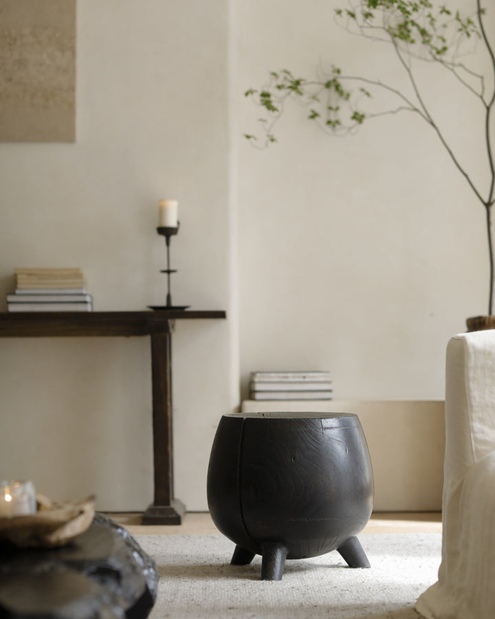 Black wooden side table in a minimalist living room setting.